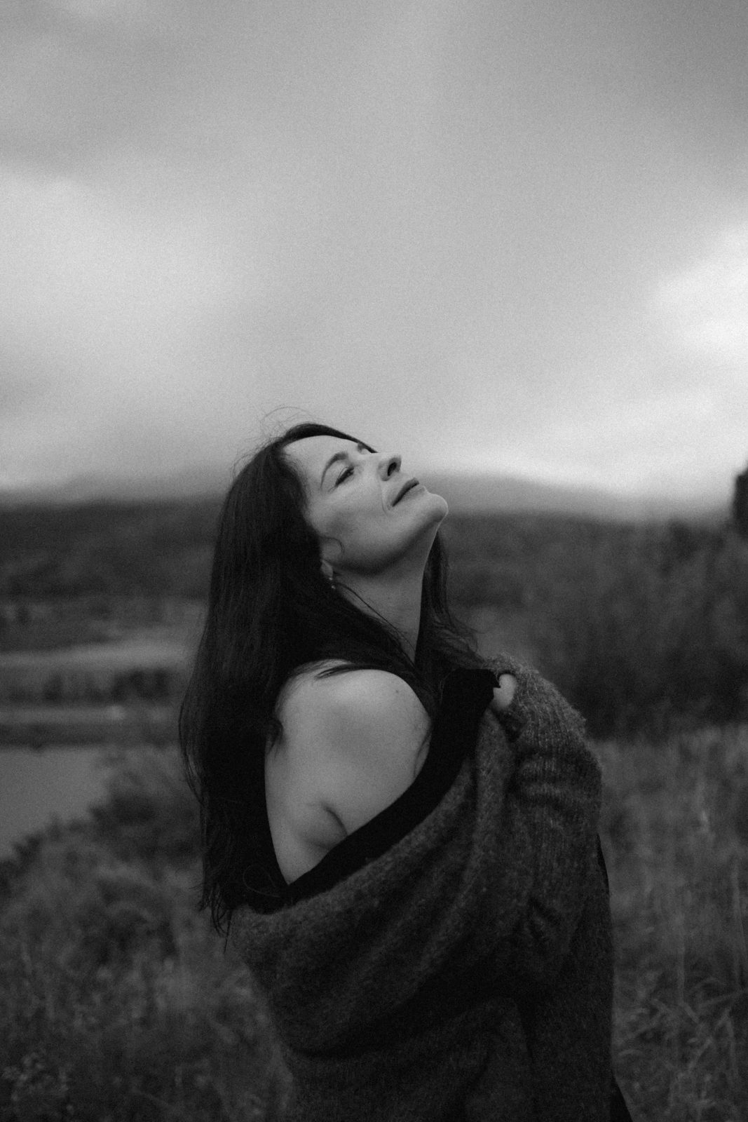 Black and white portrait of a woman lifting her face to a stormy sky