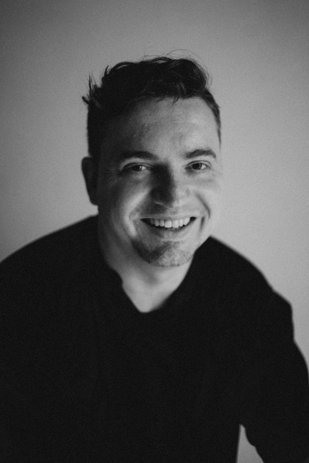 Black and white portrait of a laughing man in a dark sweater