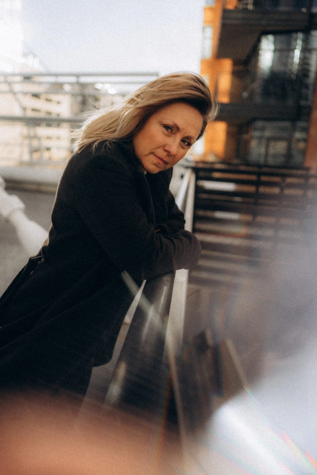 Woman in a black coat leaning on a city railing