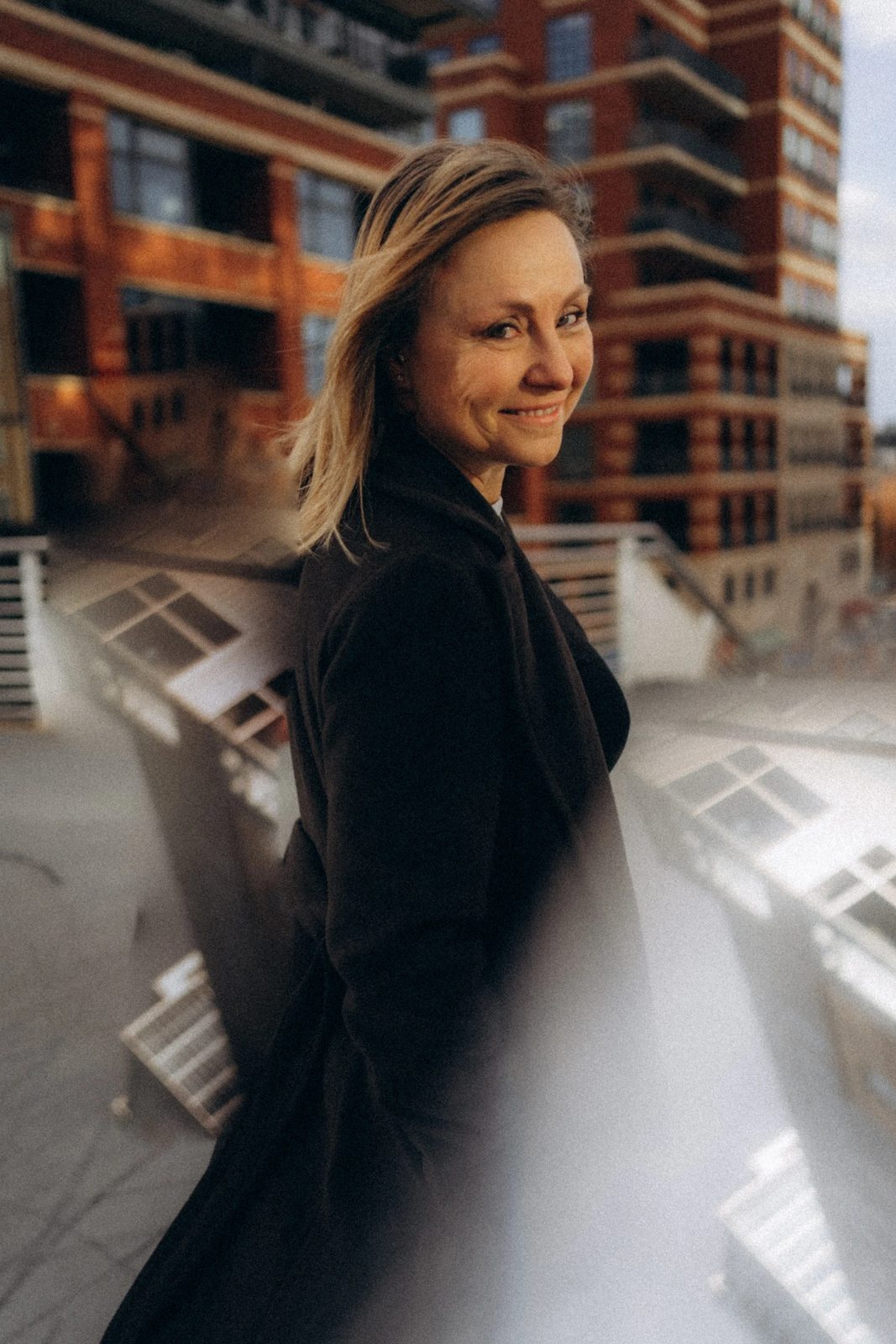 Woman in a dark coat smiling over her shoulder in downtown Denver