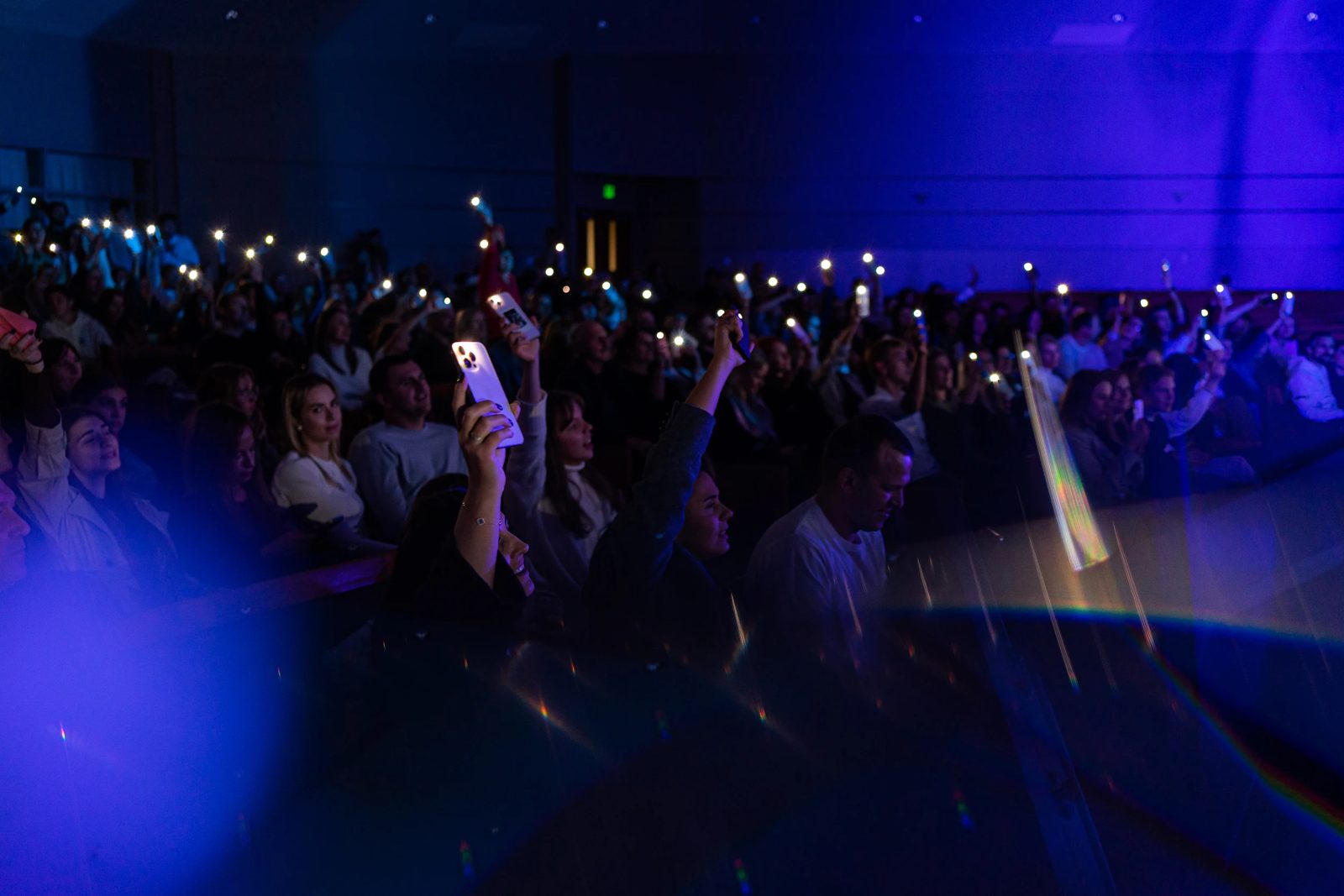Audience raising phone lights in a dark concert hall