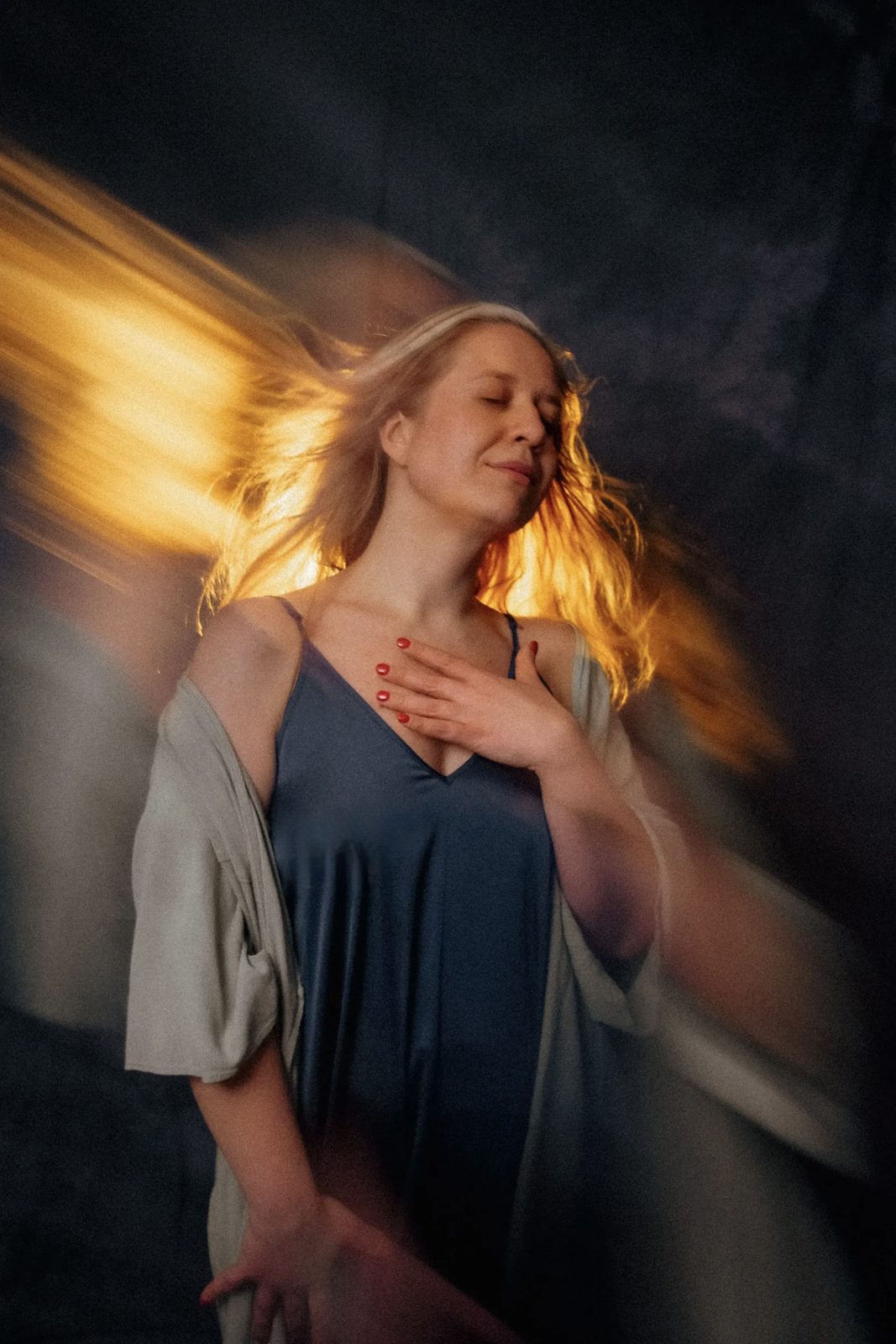 Woman with a hand on her heart as golden light sweeps through her hair