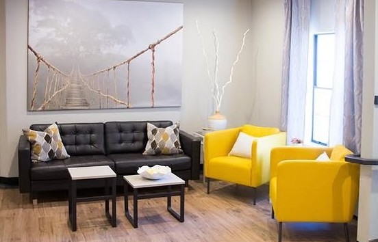 Bright lounge with a black leather sofa and two yellow armchairs
