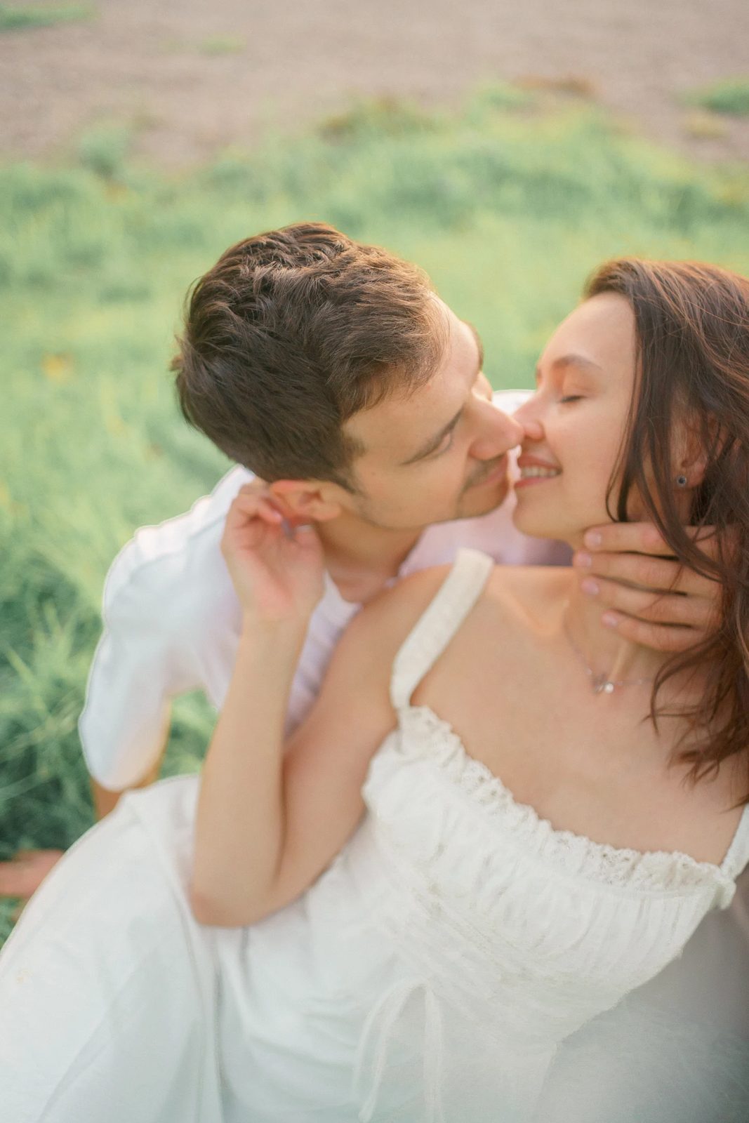 Couple nose to nose in a sunlit field