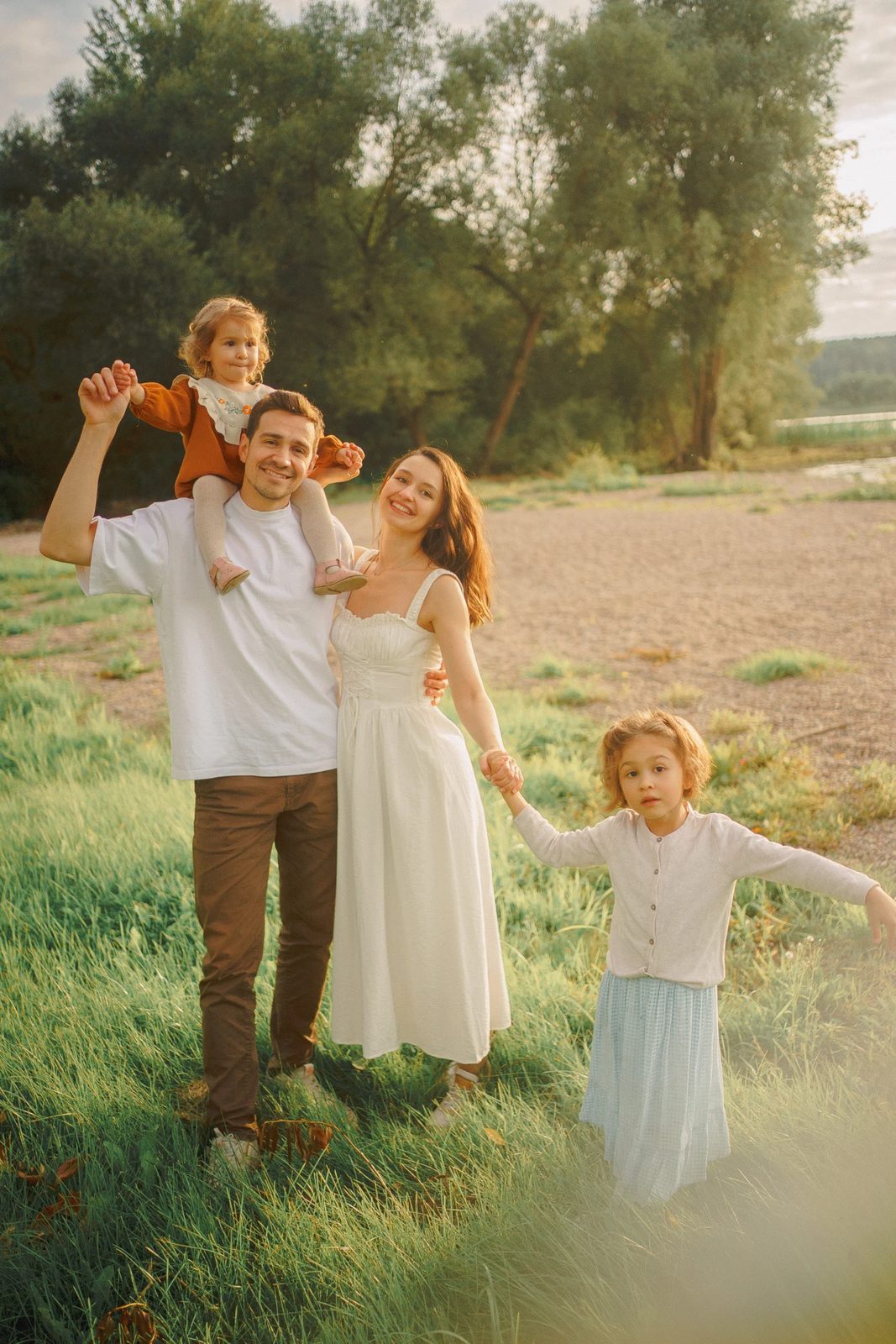 Family in a summer meadow, a toddler riding on her father's shoulders