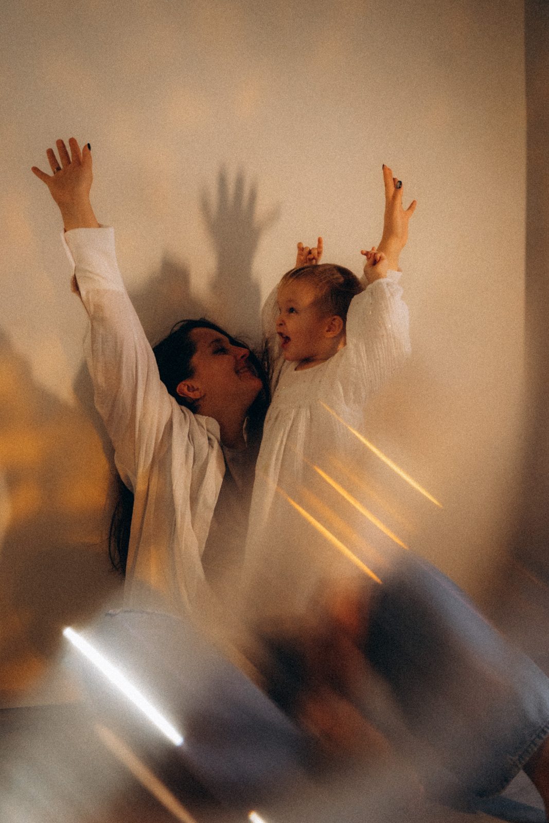 Mother and toddler throwing their arms up in streaks of warm light