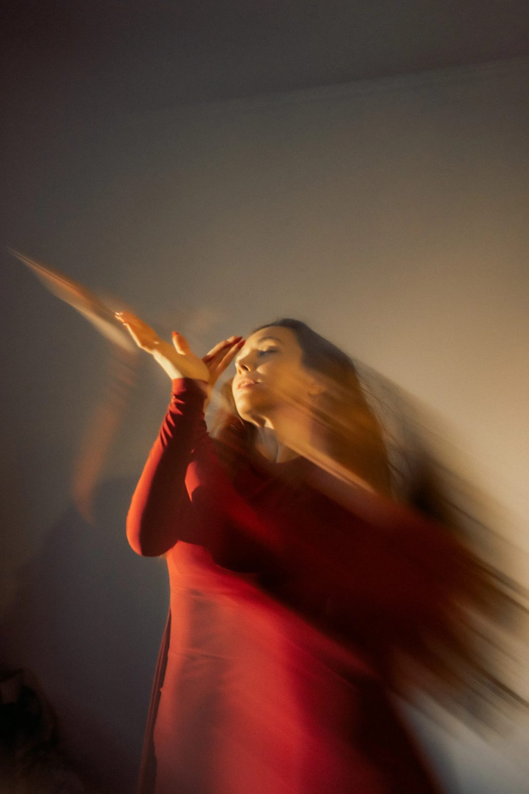 Woman in a red dress dancing, her hair streaked by motion