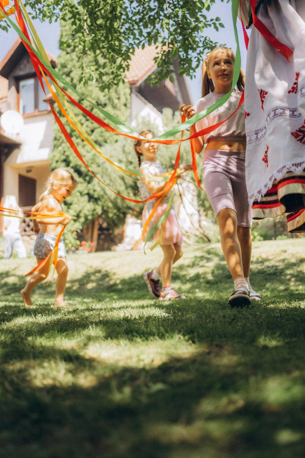 Children running with bright ribbons on a summer lawn