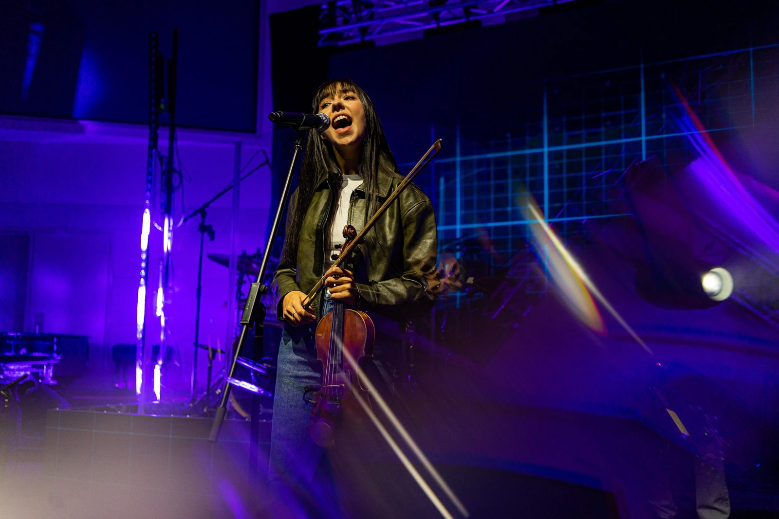 Singer with a violin performing under violet light