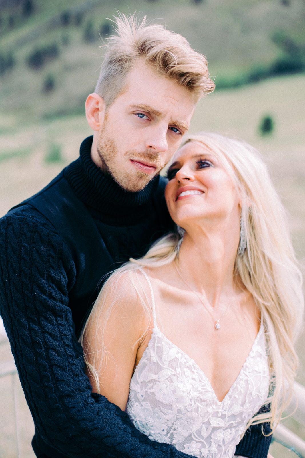 Groom looking into the camera while the bride smiles up at him